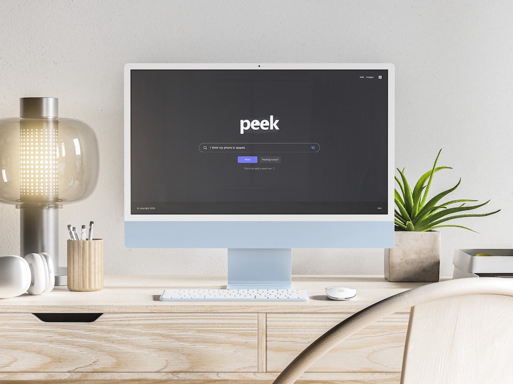 Peek search engine displaying in light blue iMac computer sitting on top of a wooden desk.